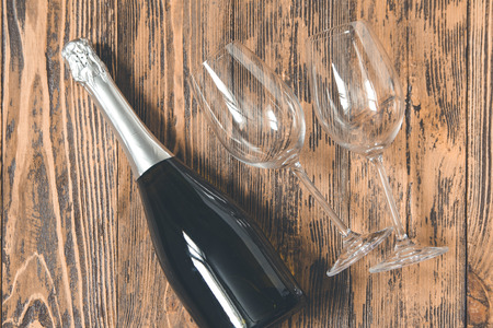 Champagne bottle and two empty wine glasses on wooden background. Wedding, Valentine's Day. Top view. Vintage style.の写真素材