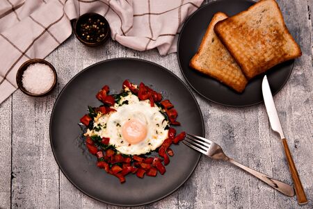 Fried eggs with peppers and tomatoes and toast for breakfast. The concept of healthy eating.の写真素材