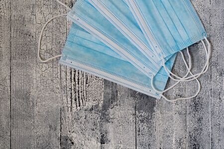 Blue medical disposable face mask on a wooden background.の写真素材