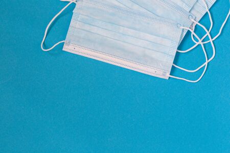 Blue medical disposable face mask on a blue background.の写真素材