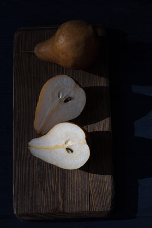 Yellow pear on a dark background. Half pear on the table. Natural healthy food. The concept of healthy vegetarian food.の写真素材
