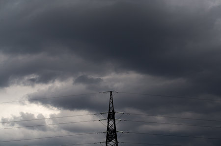 Electricity transmission pylon silhouetted against a cloudy sky.の写真素材
