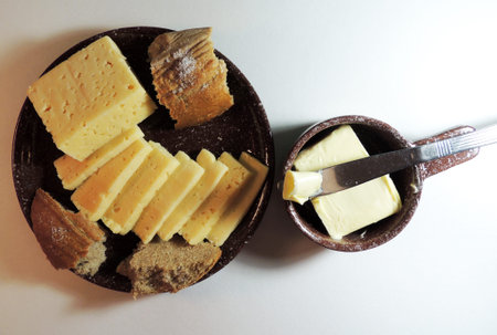 sliced cheese and chopped bread on a plate and butter on a knife