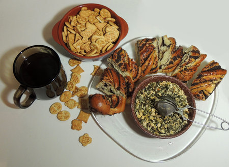 breakfast of a mug of coffee, crackers and chopped roll with poppy seeds on a transparent plate