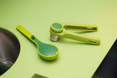 Spoon large green with holes convenient beautiful plastic for kitchen on green background, cook,...