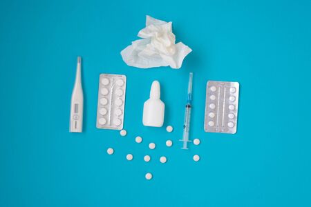 Treatment of colds and flu. Various medicines, a thermometer, sprays from a stuffy nose and a pain in a throat on a blue background. Copy space. Medicine flat lay.の写真素材