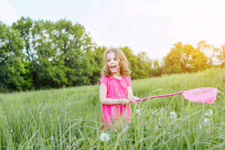 Happy baby girl catches butterflies with a pink nipple on a Sunny summer day. Holidays and children's rest conceptの写真素材