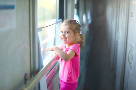 Little baby girl rides the train with her parent on a summer day. Traveling with children. Summer...