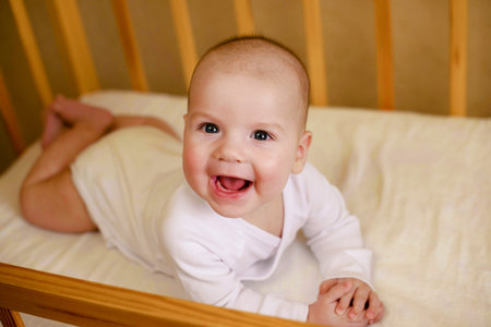Portrait of a beautiful infant baby boy 5 months old in white clothes, sleeping in his crib....