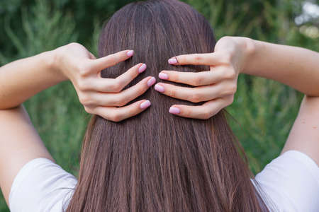 Brunette girl runs her hands through her hair. Trend. Without a face. Healthy hair and nails.の写真素材