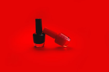 Red and black nail polish isolated on red background. Beauty, fashion, care concept.の写真素材