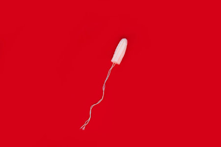 Medical female tampon on a red background. Hygienic white tampon for women. Cotton swab. Menstruation, means of protection.の写真素材