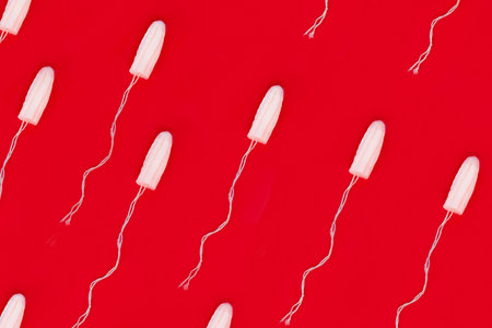Pattern medical female tampon on a red background. Hygienic white tampon for women. Cotton swab. Menstruation, means of protection.の写真素材