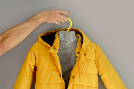 Yellow jacket gray sweater on a gray wall background. Illuminating, Ultimate gray color of the year...