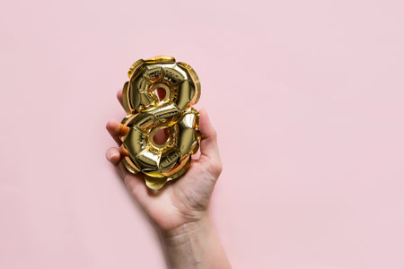 Woman's Hand holds a Golden helium balloon number 8 on a Pink Background. International Women's Day and March 8の写真素材