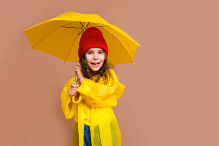 happy girl kid laughing with yellow umbrella on colored beige background.の写真素材