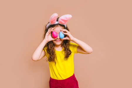 Cute girl child with Easter bunny ears holds a basket of colored eggs. Happy Easter, holidays, traditions concept.の写真素材