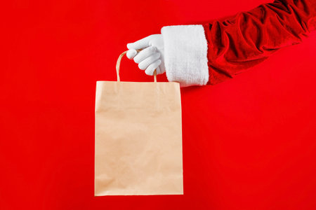 Trendy craft package in Santa's hands on a red background. Sale, contactless, holidays concept