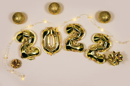 Golden 2022 balloons, gift, balls isolated on gray background. Helium balloons, gold foil numbers. Numbers for Happy New Year 2022. Party decoration, celebration, carnival.の写真素材