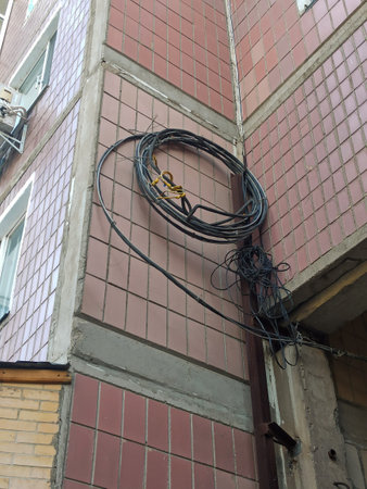 black wires coiled in a circle hang on a nail on a burgundy wallの写真素材