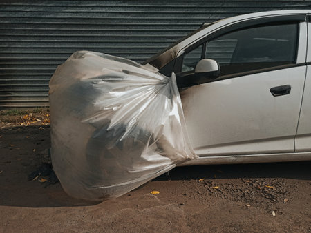 Car covered with a plastic bag on the street. Pollution of the environment.の写真素材
