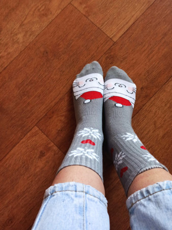 Feet in woolen socks on the wooden floor, top view