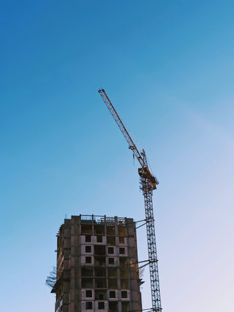 Silhouette of a construction crane on a background of blue sky