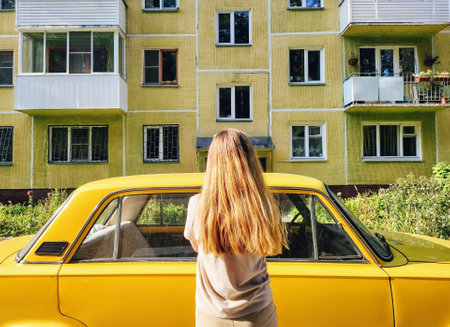 Back view of young woman looking out the window of a yellow retro carの写真素材