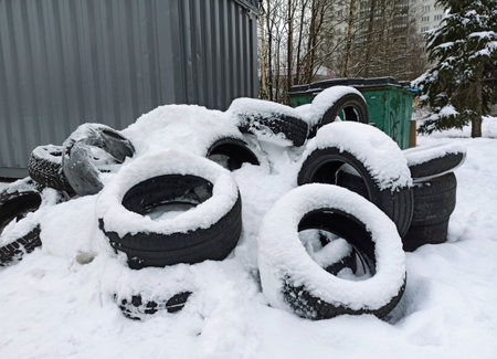 Old car tires covered with snow after a heavy snowfall in the cityの写真素材