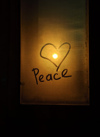 Heart shape lit on a window with the word Peace written in it