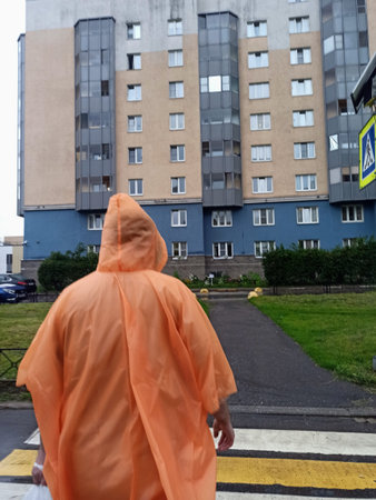 Rear view of a man in raincoat walking on the streetの写真素材