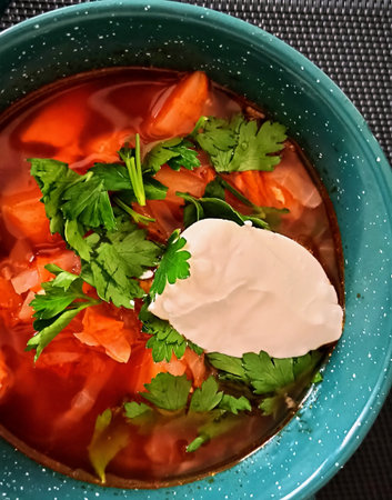 Borscht with sour cream and parsley in a blue bowl