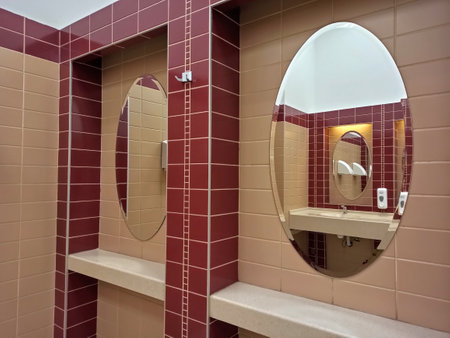 Interior of a bathroom with red tile wall and two round mirrorsの写真素材