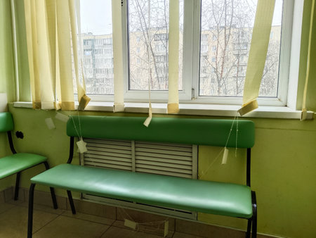 Interior of a hospital corridor with green chairs and a window.の写真素材