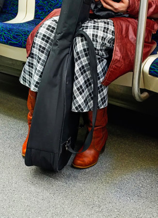 A man in a red jacket and brown boots is sitting on a train.の写真素材