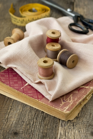 Old spools of thread, fabric, scissors on a wooden の写真素材