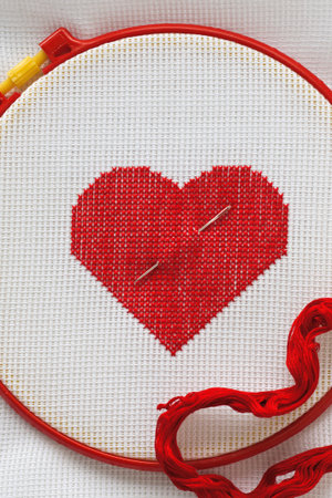 red heart embroidered with a cross on a white canvas