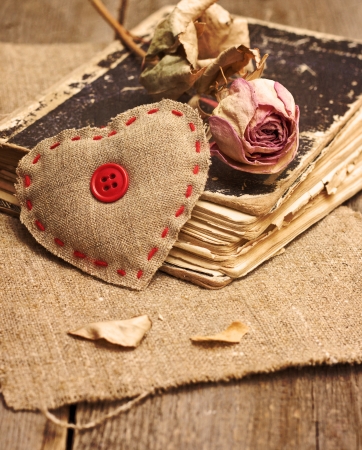Valentine decorations with heart, dry rose, old book on a wooden background ( toning, grunge).の写真素材