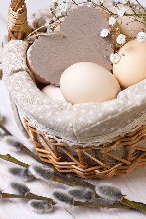 basket with eggs, wooden heart and willow branches on a wooden backgroundの写真素材