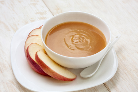 caramel sauce in a bowl and apple slices on a white plateの写真素材