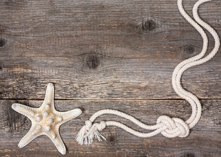 Starfish and rope on a wooden background (sea decoration)の写真素材