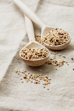 two wooden spoons with quinoa on a linen backgroundの写真素材