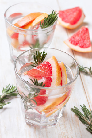 detox water with grapefruit and rosemary, ice in glasses on a white wooden backgroundの写真素材