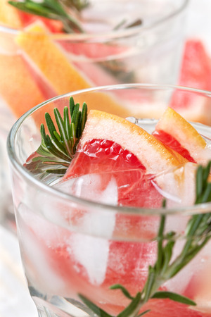 detox water with grapefruit and rosemary, ice in glasses on a white wooden backgroundの写真素材