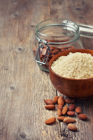 almond flour in a wooden bowl, almonds on old wooden background (Toning)の写真素材
