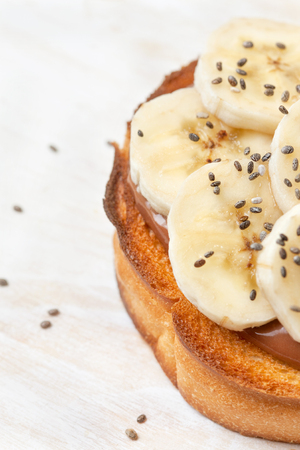breakfast toast with banana and chocolate cream, chia seeds  on a white wooden backgroundの写真素材