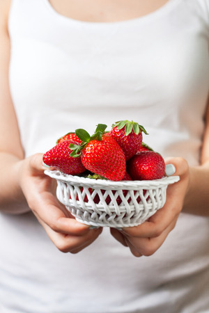 girl holds in hands bowl of fresh strawberriesの写真素材