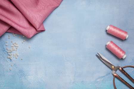 Tools for sewing: the fabric, scissors, pins, tape measure on blue concrete background (top view)の写真素材