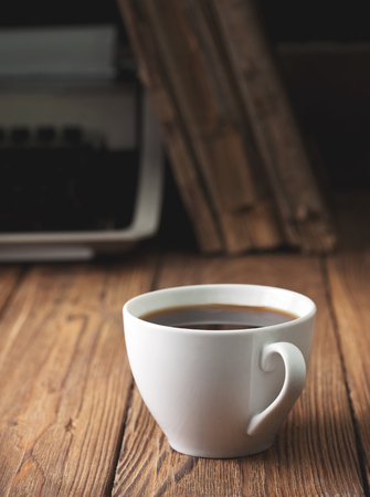 cup of coffee and old typewriter on old wooden background. Concept. Dark.の写真素材