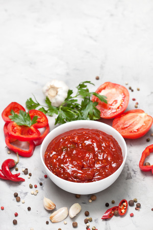 tomato sauce in a white bowl, fresh tomatoes and parsley on a gray concrete background. view from aboveの写真素材
